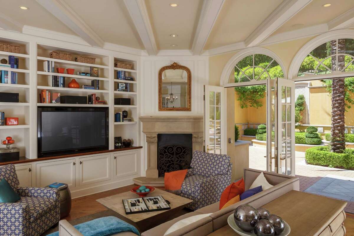 Floor-to-ceiling built-in bookshelves, three sets of French doors opening to the backyard and a beamed ceiling highlight the living room. 