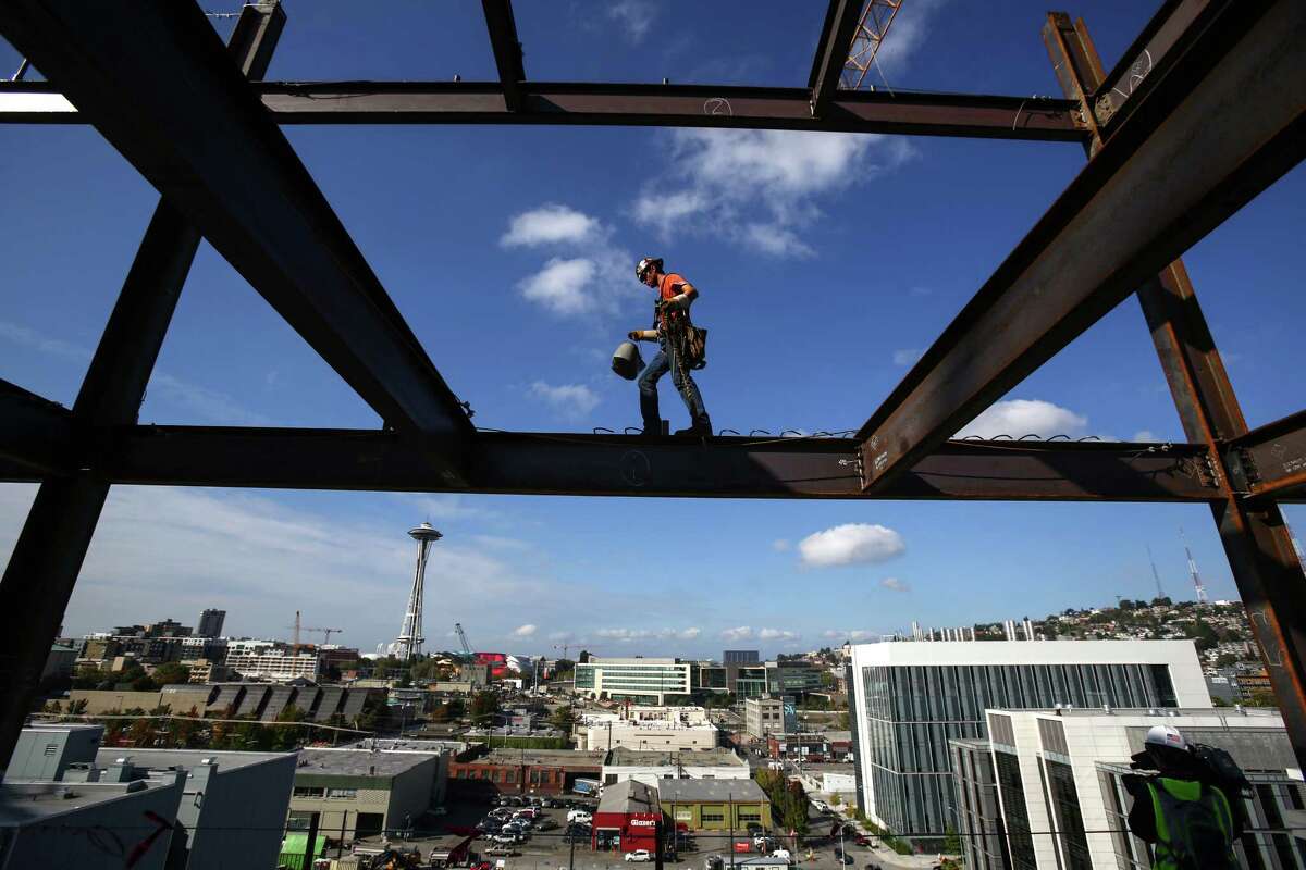Iron worker Jake Lucas balances as he negotiates a beam on the 11th floor of Vulcan's Block 45 Project in South Lake Union. The building is being assembled faster than most as two tower cranes are being used on the project. When finished the building will be 12 stories tall and almost 500,000 total square feet. Photographed on Thursday, October 2, 2014.