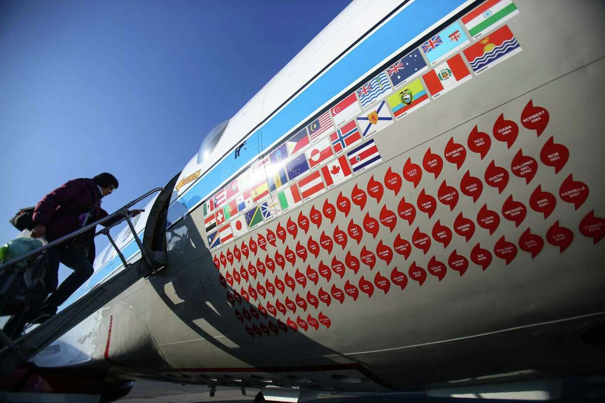 University of Washington research scientist Muyin Wang boards the National Oceanic and Atmospheric Administration's P-3 "hurricane hunter" for departure from Boeing Field for a mission to the Arctic. The red decals show the many storms the aircraft has entered to take measurements.