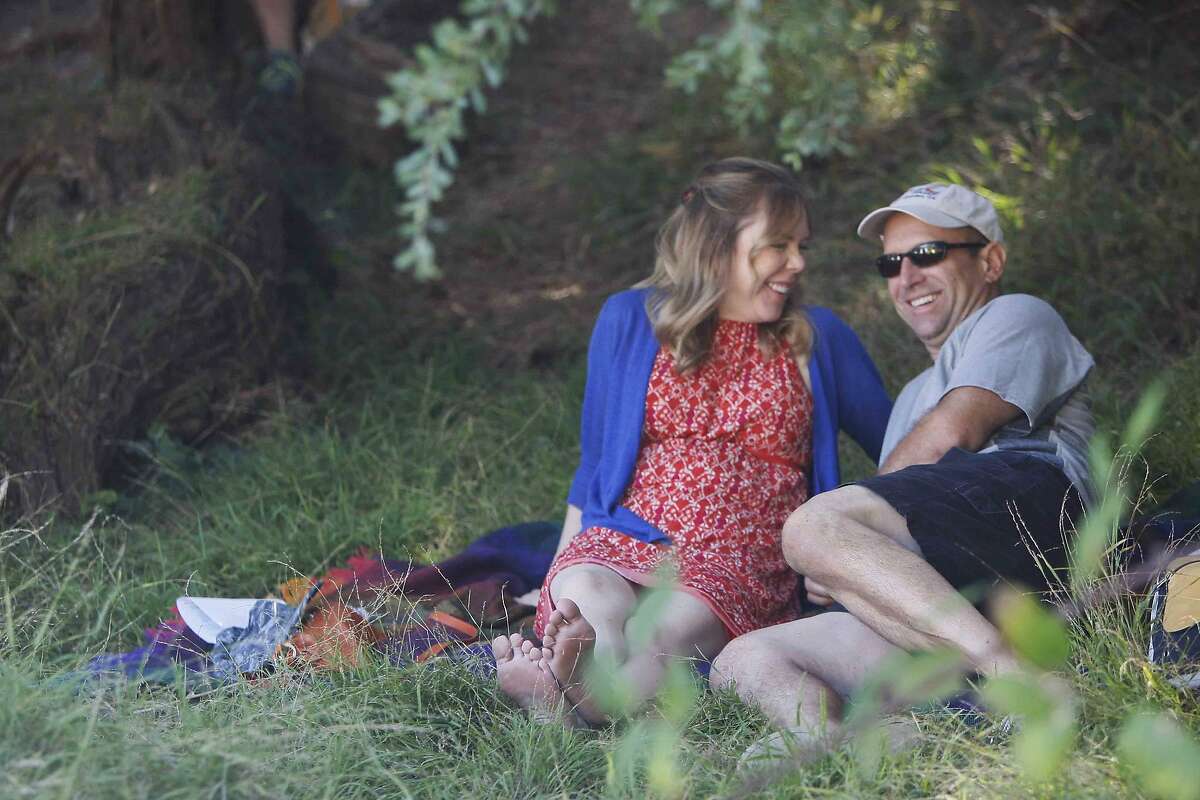 Kelly Lanspa (left) and Hugh Scollan of San Jose escape the heat under shaded trees while watching live music at the Hardly Strictly Bluegrass Festival in San Francisco's Golden Gate Park Friday, October 3, 2014.