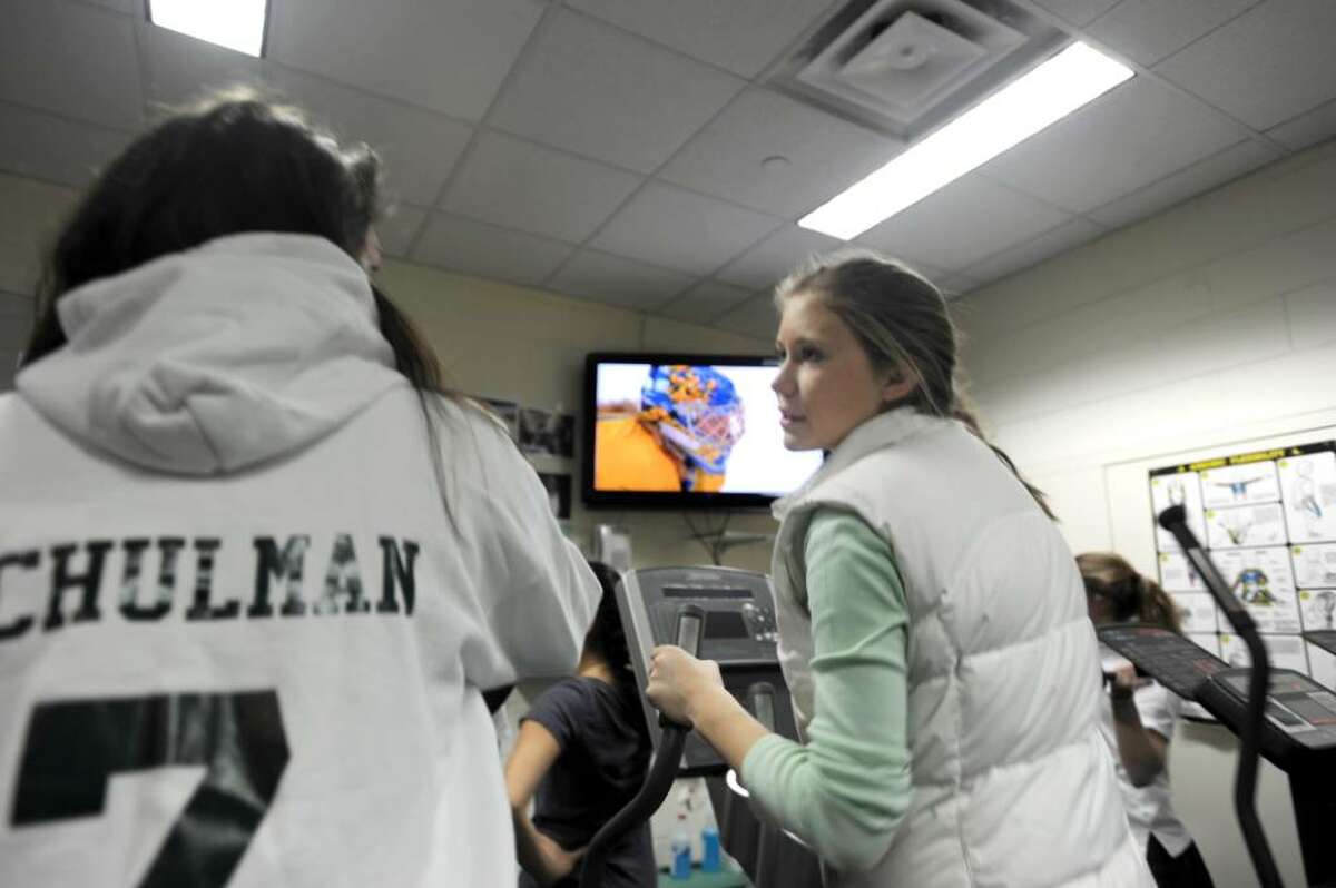Pam Schulman, a freshman left, and Eliza Hompe, a senior, both Greenwich Academy varsity hockey players, watch the USA Women's Team semi-final game at the Olympics, while working out at Greenwich Academy, on Monday, February 22, 2010.