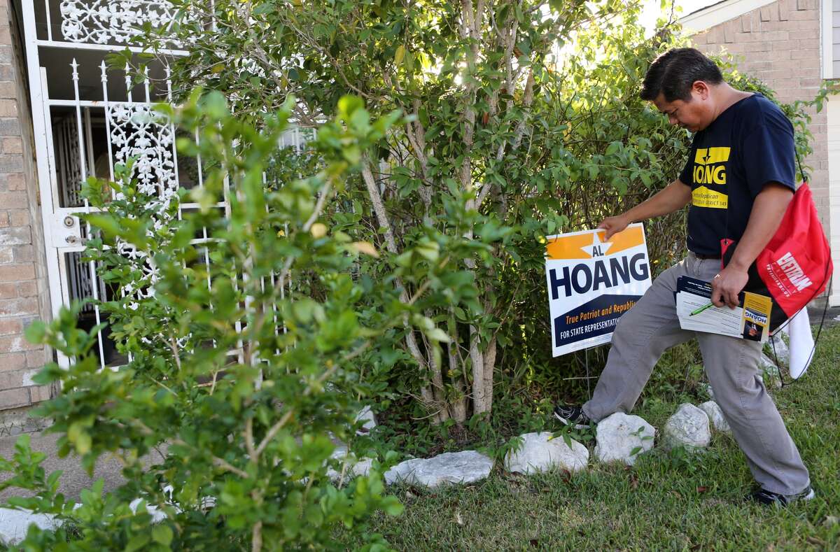 Al Hoang, Republican Candidate for State Representative, District 149, places a sign in front of a home while speaking with Asian and Asian-American voters during his block walk on Wednesday.
