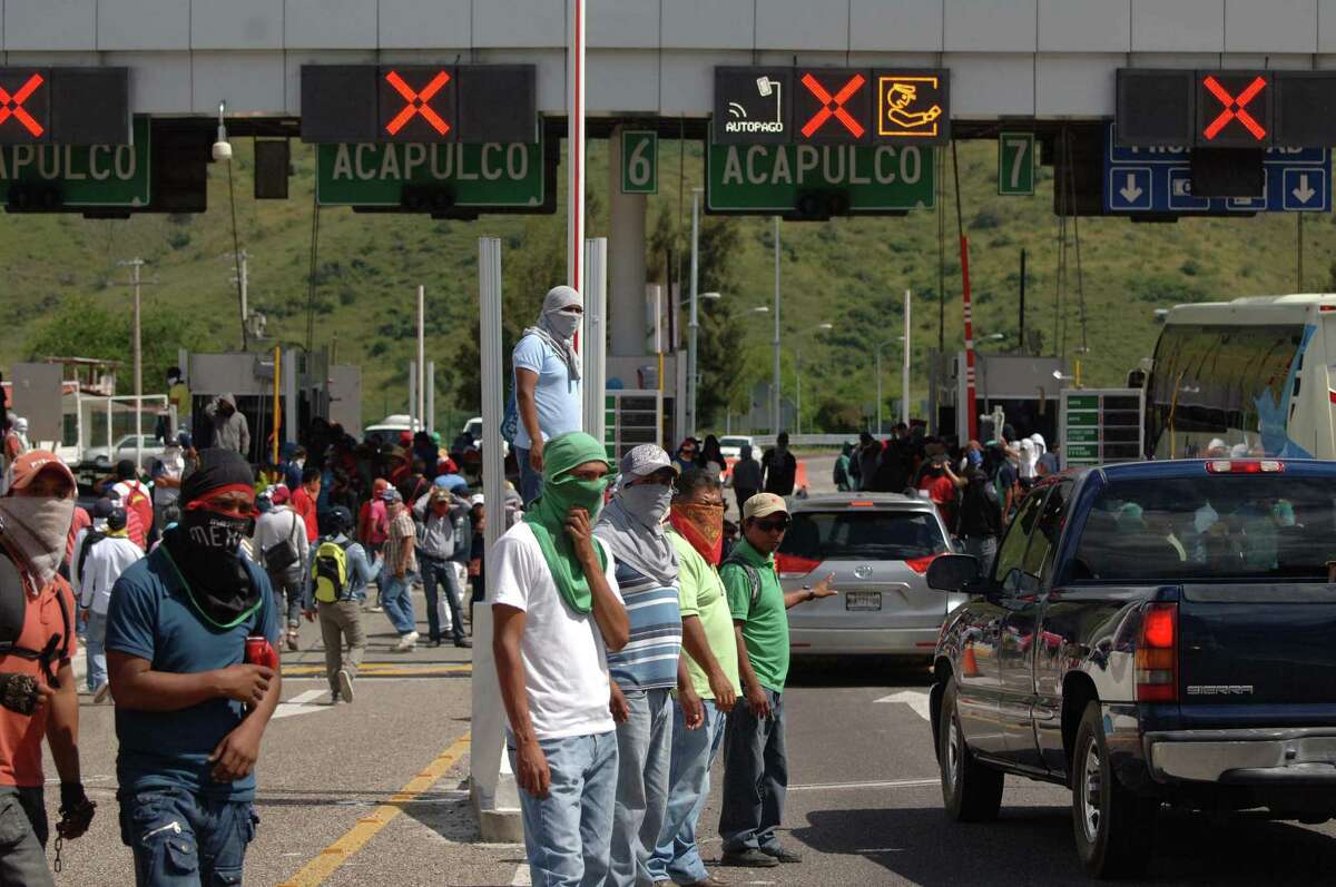 Students and relatives of missing students occupy a toll booth as they block a main highway into the city of Chilpancingo, Mexico, Sunday Oct. 5, 2014. Students and relatives are demanding answers a day after security forces investigating the role of municipal police in clashes in this southern city a week ago found a mass grave, raising fears the pits might hold the bodies of 43 students missing since last week in the violence that also resulted in six shooting deaths. (AP Photo/Alejandrino Gonzalez)
