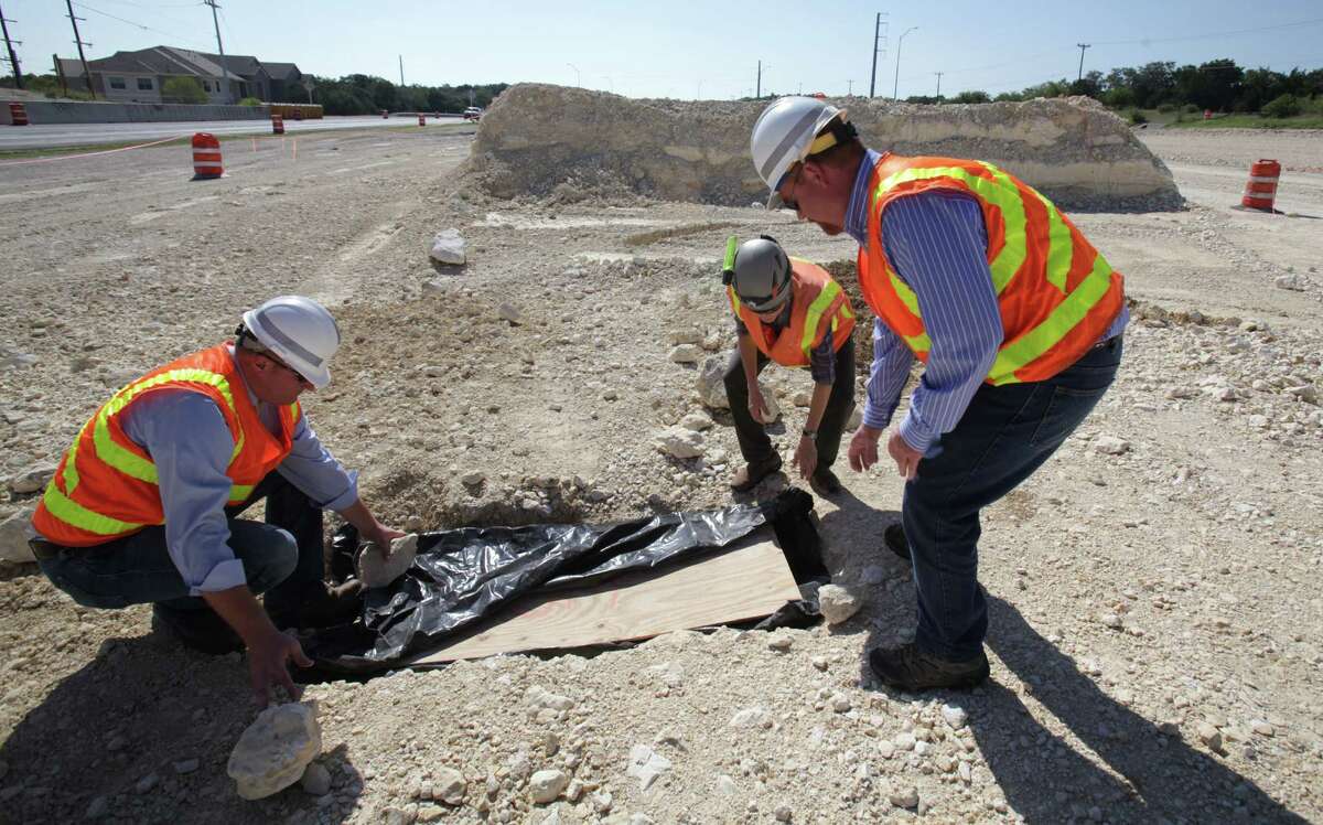 TxDOT workers Joshua Donat, left, Stirling Robertson, right, and Biologist Jean Krejca, center, inspect a small cave they found as construction workers were grading land along Texas 151 near Loop 1604 for an underpass. Endangered spiders were found in the small feature, halting construction work as Biologist study the rare spiders Friday, Sept. 7, 2012.