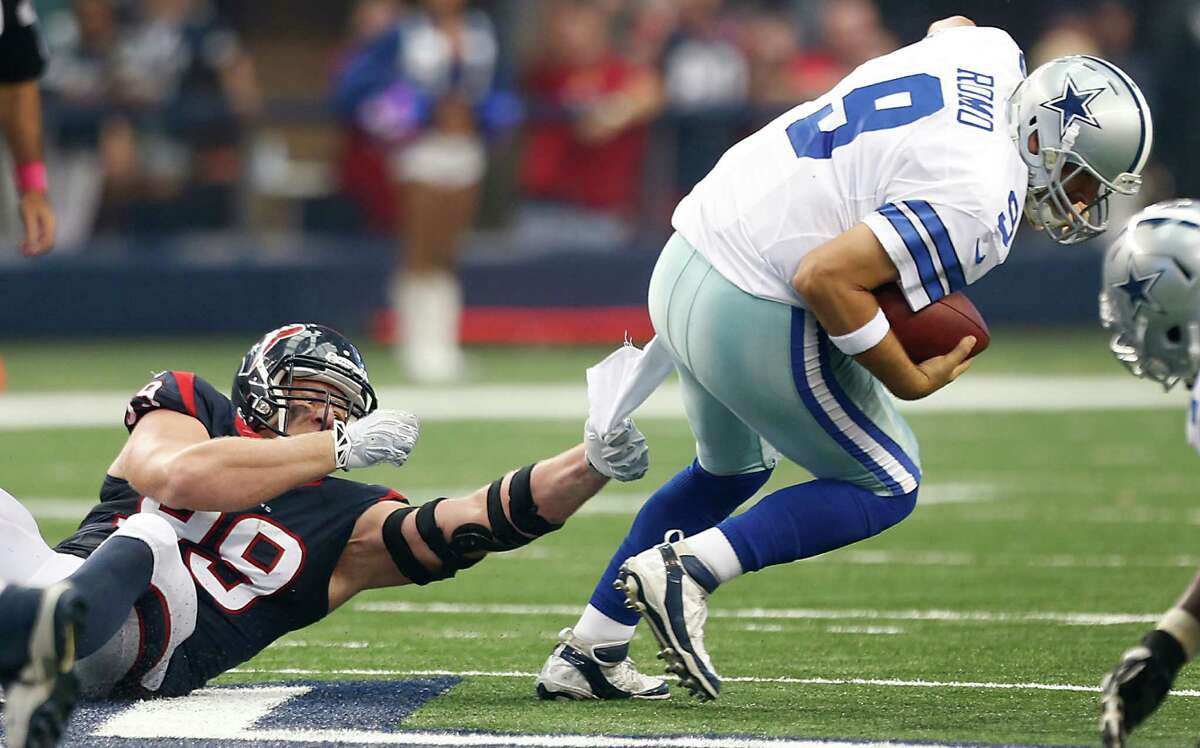 Cowboys quarterback Tony Romo (9) somehow manages to escape the grasp of Texans defensive end J.J. Watt before completing a 43-yard touchdown pass to wide receiver Terrance Williams during the third quarter of Sunday's game at AT&T Stadium in Arlington.