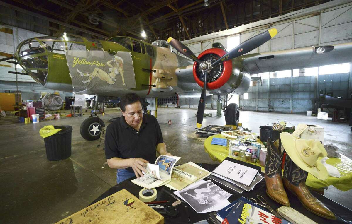 Artist Fernando Cortez looks through reference material as he works on nose art of a World War II vintage bomber B-25 bomber, nicknamed the “Yellow Rose,” which belongs to the Commemorative Air Force and is hangared at the San Marcos Municipal Airport.