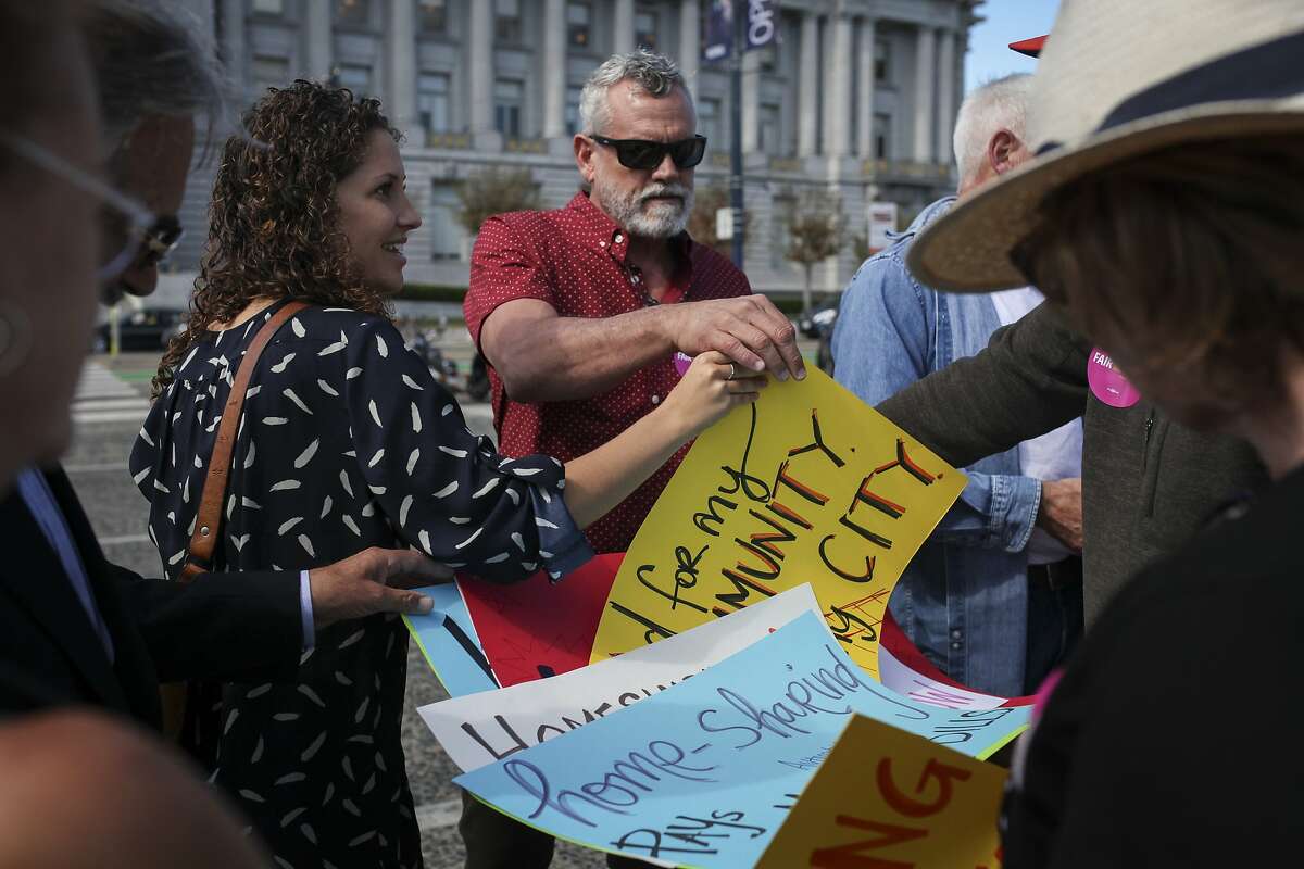 Gregg Demeza, a 8 month Airbnb host from Bernal Heights grabs a sign during a rally held by Home Share SF, at Civic Center Plaza in San Francisco on October 7th 2014.