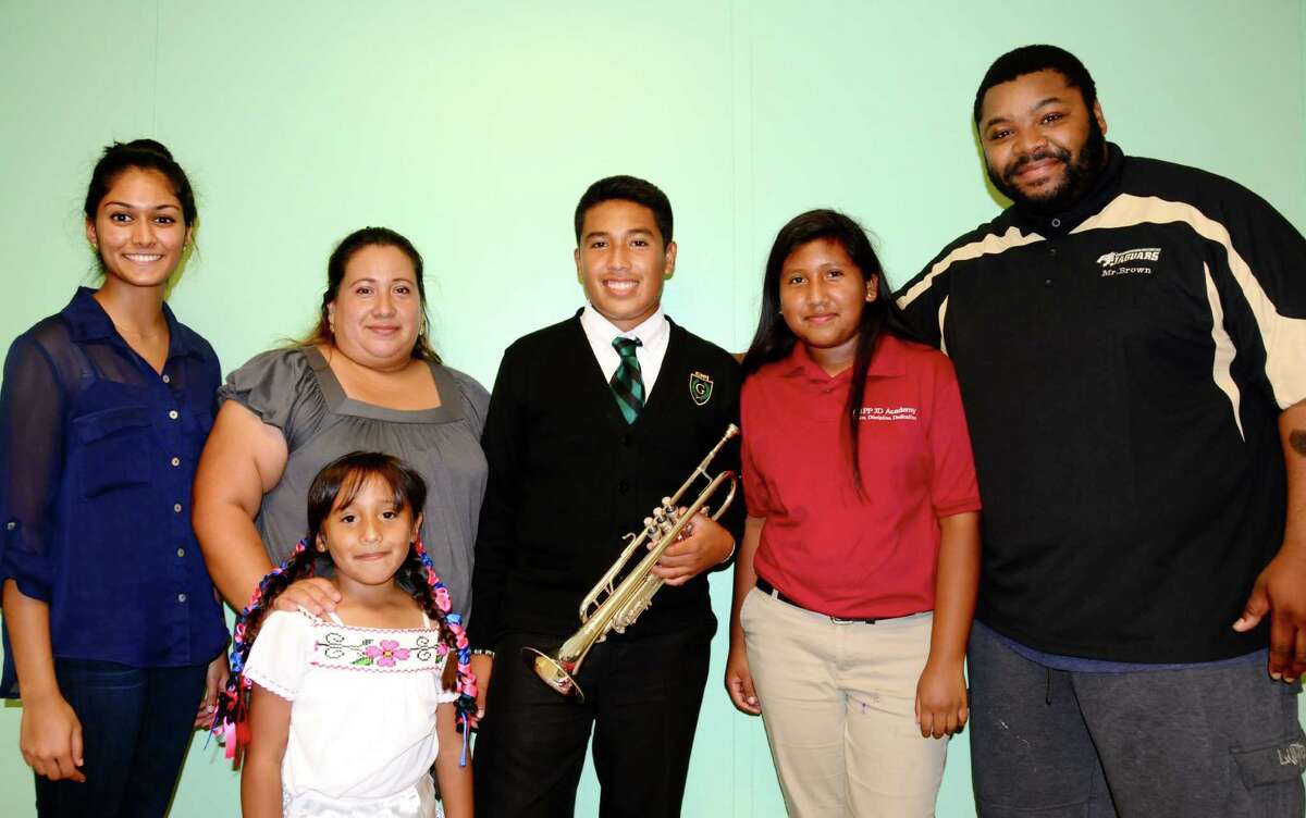 Surrounded by his family, Eduardo Ponce, center, holds a trumpet he received from Simple Gifts, the organization started by The Woodlands High School alum Niki Patel (left).