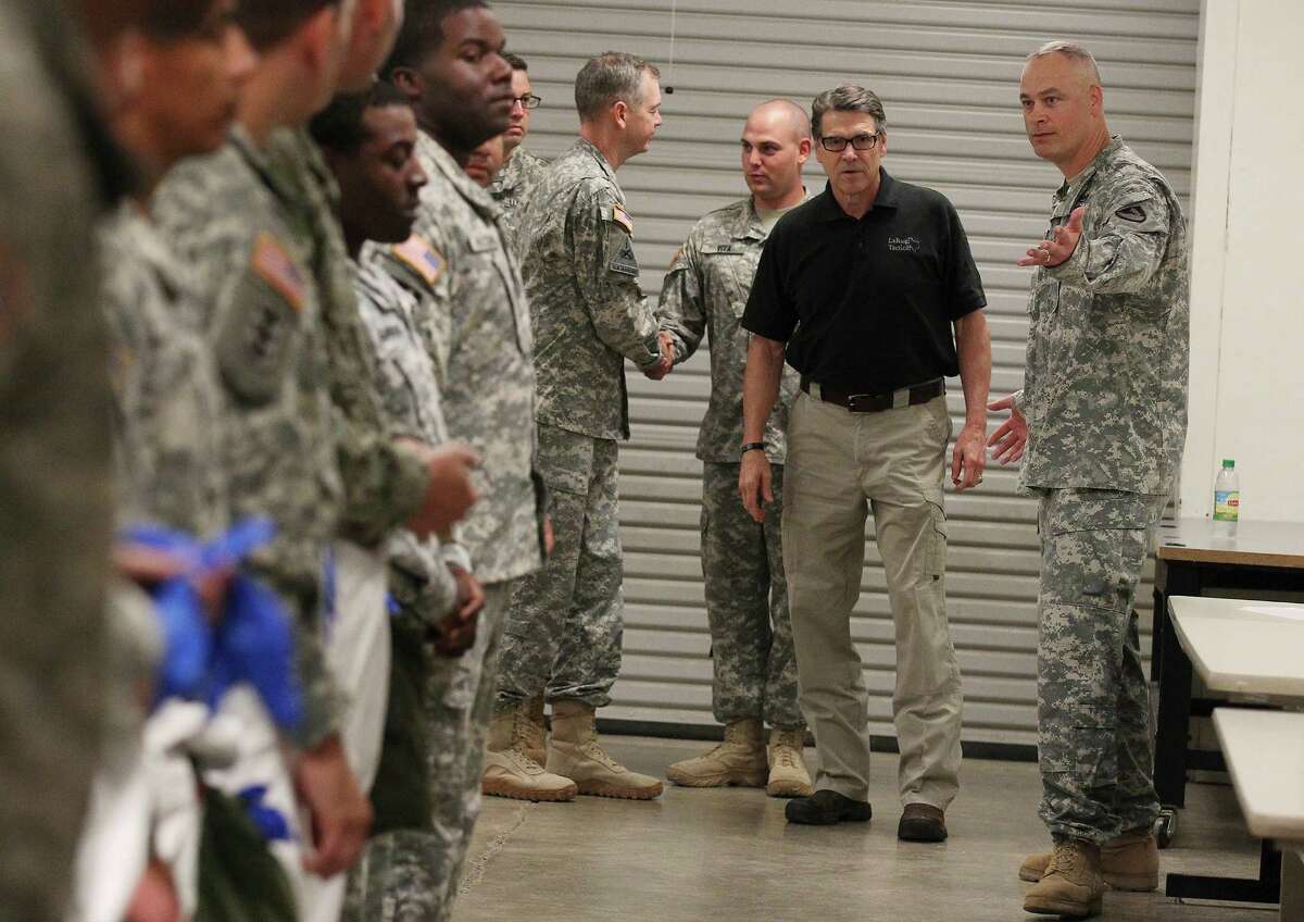 Texas Gov. Rick Perry (center) escorted by Col. Heath Roscoe (right) of the 36th Engineer Brigade meet with soldiers at Fort Hood as they train on how to put on and wear protective clothing and gloves on Thursday, Oct. 9, 2014. The brigade is set to deploy to Liberia as part of Operation United Assistance where they will be building temporary medical facilities in helping the country fight the Ebola virus outbreak. The 450 soldiers from the brigade will be amongst the first to be deployed from Fort Hood to Liberia.