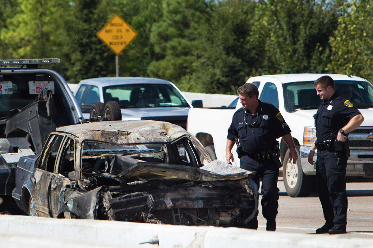 Police officers look at a burned out car, that rear-ended a garbage truck, as they investigate an accident that resulted in a fire on the southbound lanes of 249 near Greens Road on Thursday, Oct. 9, 2014, in Houston.