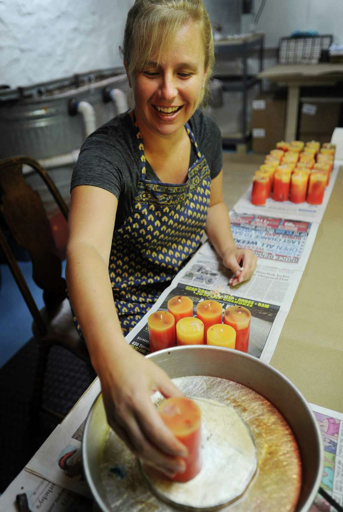 Jenn Heatly, owner of Zena Moon, melts smooth the bottoms on a batch of scented candles, the final step in her manufacturing process, in the basement of her Norwalk home on Thursday, October 9, 2014.