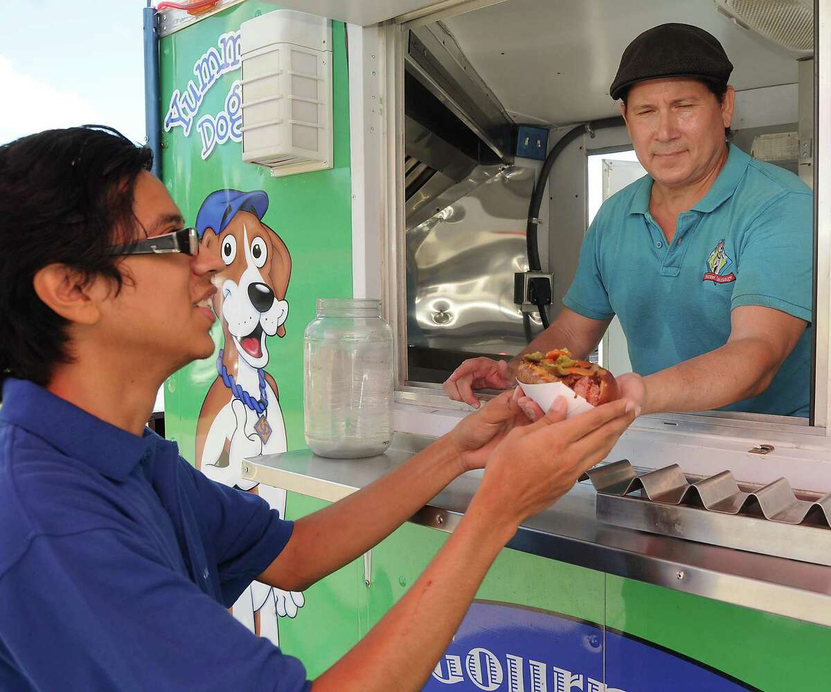 Mario Morales serves Erick Navarro a Texan Dog at his Yummy Dog food truck on Durham Thursday Oct 09, 2014.(Dave Rossman photo)