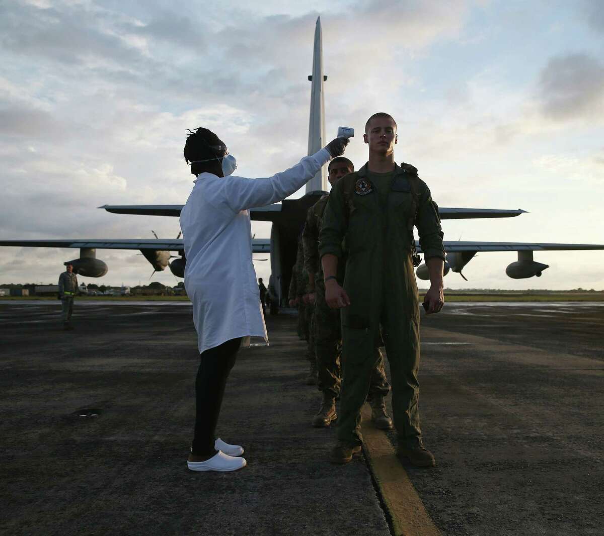A health worker takes the temperature of U.S. Marines arriving to take part in Operation United Assistance near Monrovia, Liberia. Some 90 Marines landed on KC-130 transport planes and MV-22 Ospreys.