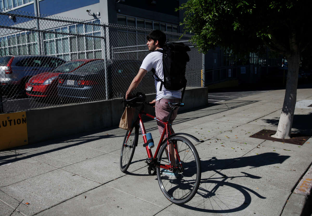 Josh Irwin, above, walks his bike up to Lyft headquarters to make a delivery from Blue Bottle Coffee during his shift with the WunWun delivery service, which is run through a smartphone app, below.