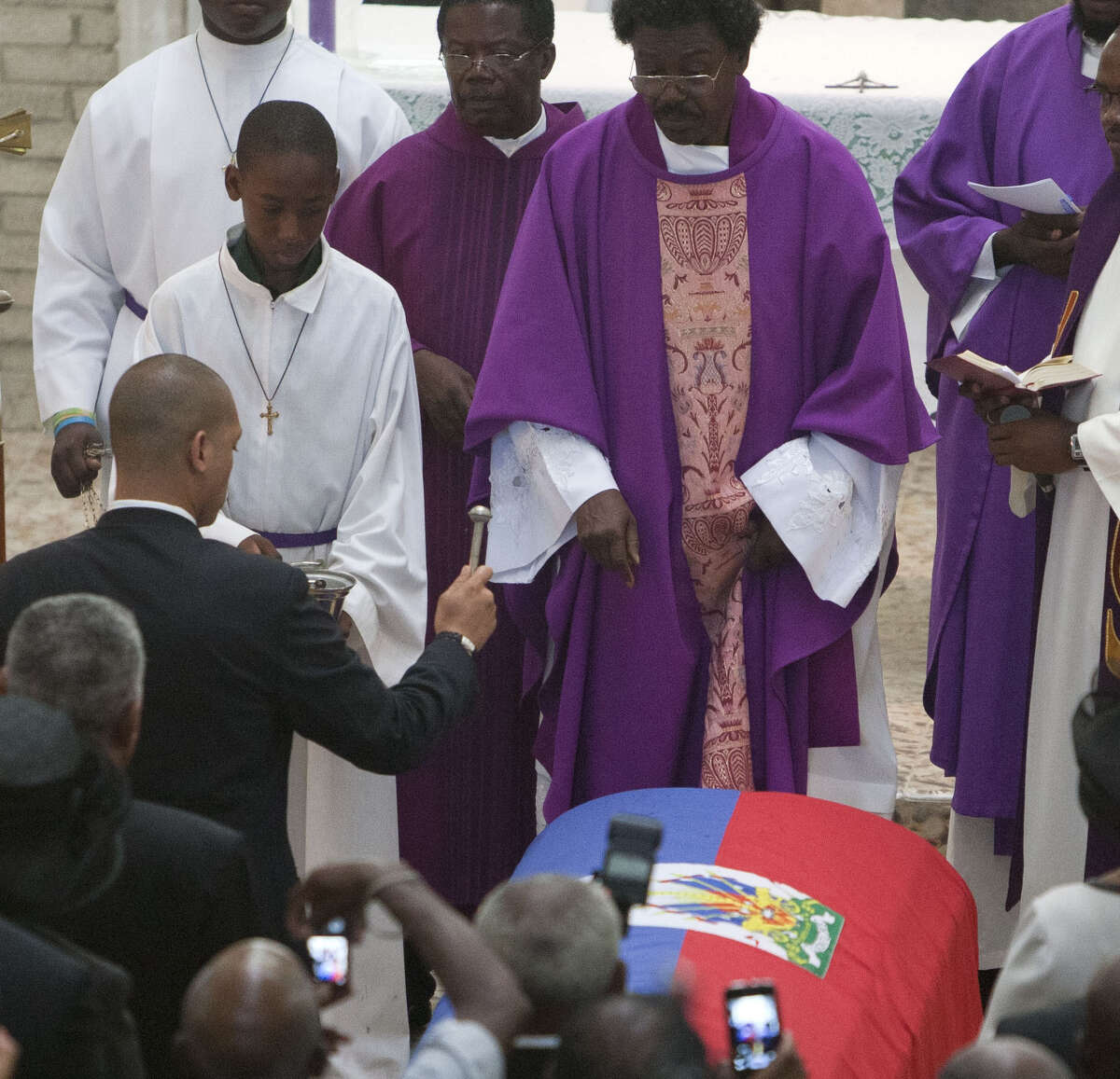 Francois-Nicolas Duvalier (left), the son of Haiti's late dictator Jean-Claude “Baby Doc” Duvalier, sprinkles blessed water on the coffin of his father in Port-au-Prince.