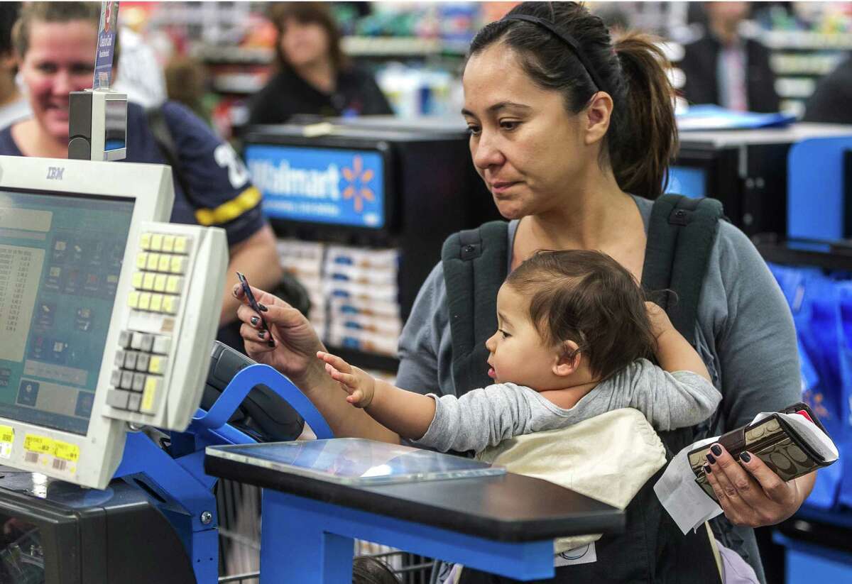 Consumer Eva Cevallos with her eleven-month daughter, Quinn, pays with a credit card, as she shops for Thanksgiving celebrations at the Pre-Black Friday event at the Walmart Supercenter store in Rosemead, Calif., Wednesday, Nov. 21, 2012. (AP Photo/Damian Dovarganes)