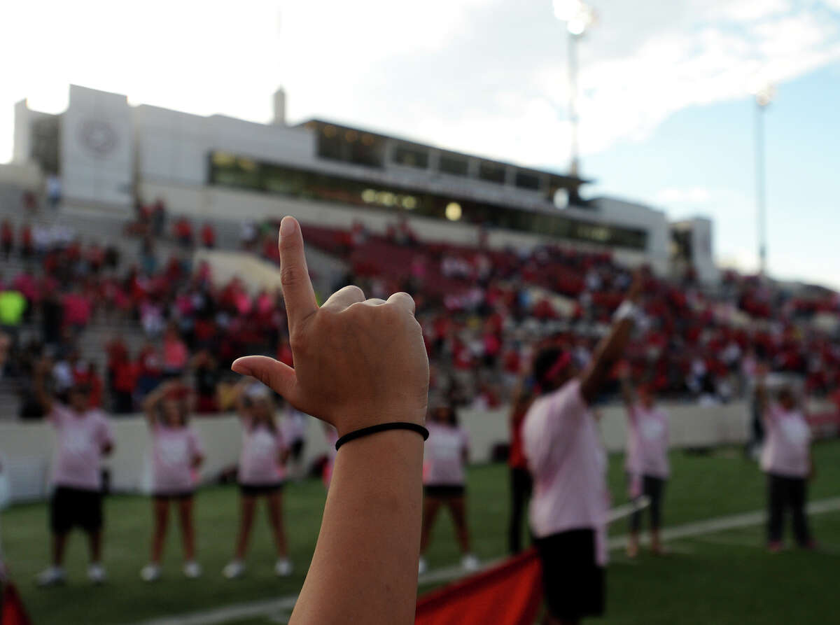 Lamar cheerleaders form an "L" with their fingers while the band plays the school song Saturday. The Lamar Cardinals hosted the Southeastern Louisiana University Lions at Provost Umphrey Stadium on Saturday night. Photo taken Saturday 10/11/14 Jake Daniels/@JakeD_in_SETX