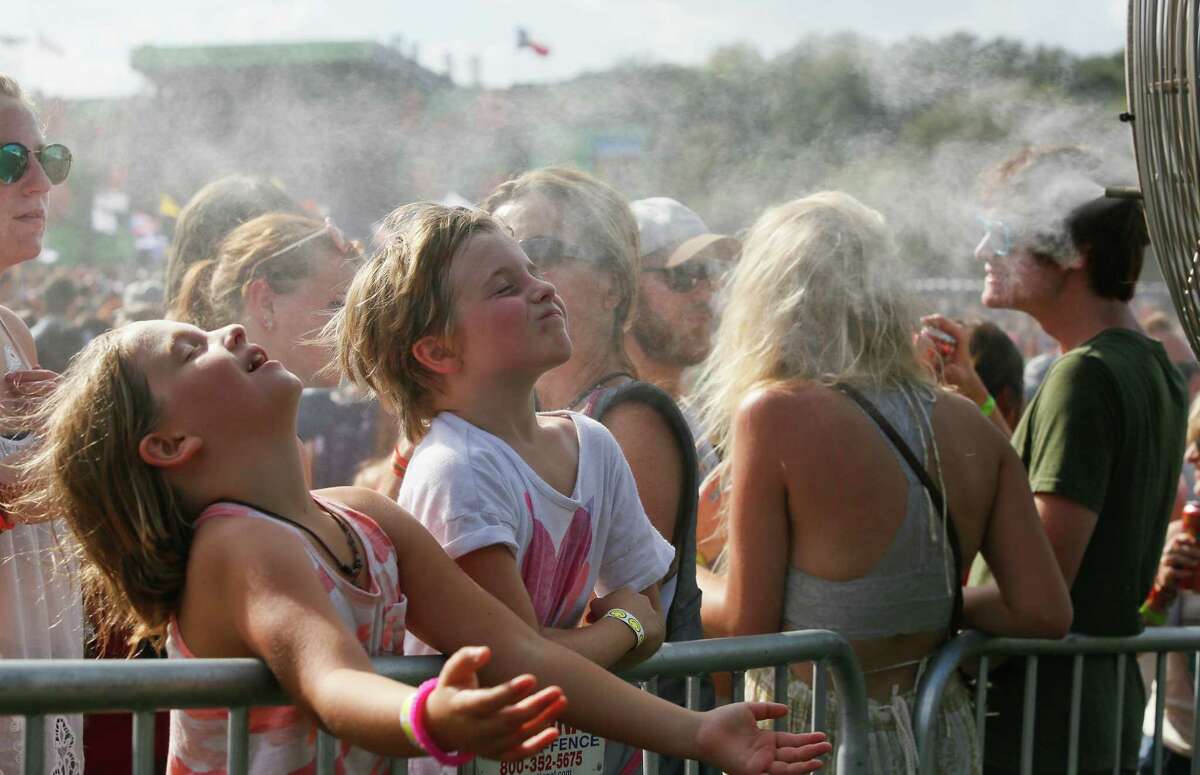 Ivy Allen, left, and sister Claire, both 8, enjoy a misting fan set up at the Austin City Limits Music Festival on Friday, Oct. 10, 2014, in Austin, Texas. (Photo by Jack Plunkett/Invision/AP)