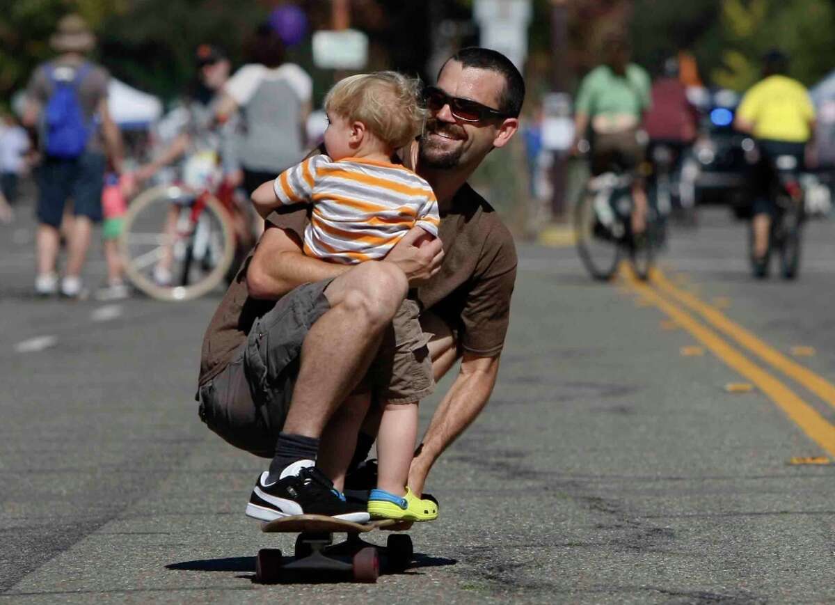 Sai Duhamel rolls down Shattuck Avenue with Donovan Fernandez, 2, during Berkeley’s annual Sunday Streets. Some 50,000 people showed up for the vehicle-free party.