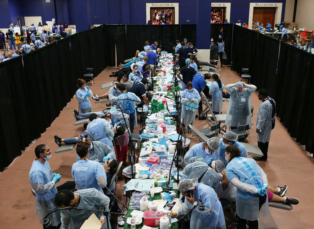 ABOVE: A team of 938 volunteers joined in to provide free services during Sunday's Mission of Mercy clinic at the Convention Center. In the count were 161 dentists and 443 community volunteers. They were from 36 states and 10 countries. The clinic was part of the American Dental Association convention, and its goal was to provide services to more than 1,000 individuals in 12 hours. LEFT: Jessica Herrera (left) and Hiral Gandhi get their picture taken with the “Tooth Fairy,” Dr. Lisa Masters, during the clinic.