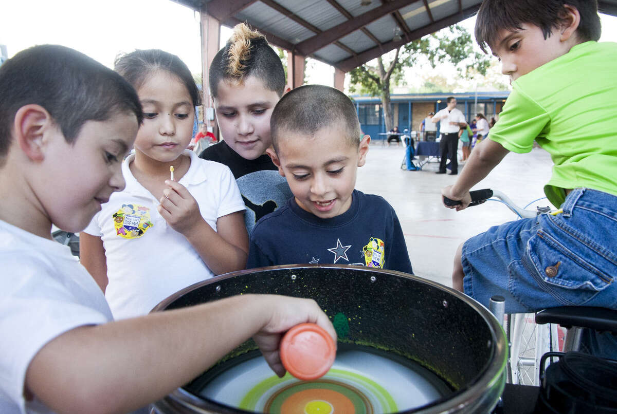 Gabriel Peña (from left), 7, Mia Flores, 8, Brandon Fernandez, 9, Jacob Gomez, 7, and Salome Luna, 8, create a painting by pouring paint onto a spinning table generated by a bicycle.