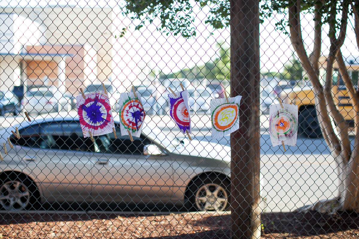Paintings hang on a fence to dry, created by children pouring paint onto a spinning table generated by a bicycle Tuesday October 7, 2014 during National Nigh Out at the Guadalupe Community Center hosted by Catholic Charities Archdiocese of San Antonio.