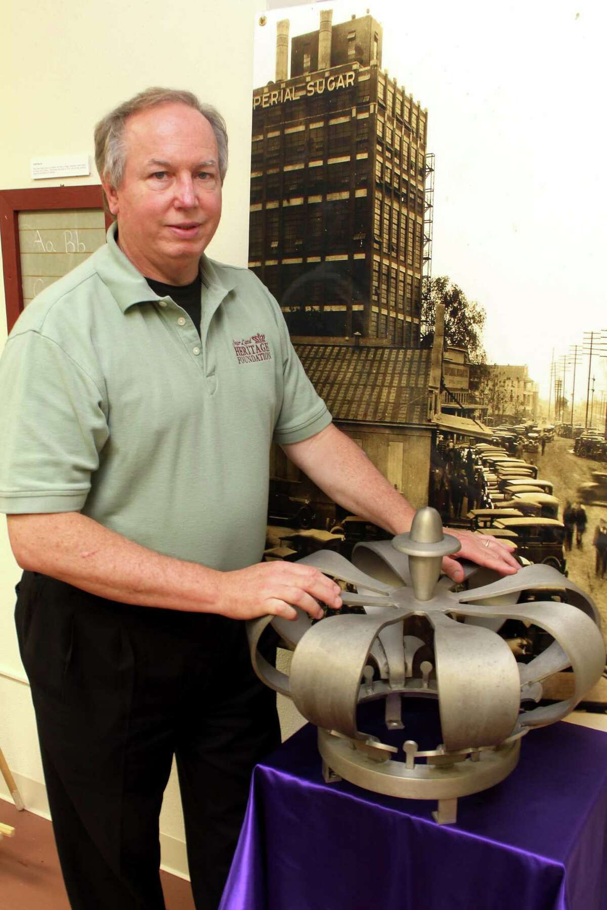 Dennis C. Parmer, Executive Director, Sugar Land Heritage Foundation, stands beside one of two Imperial crowns; one crown stood at the gate entrance as workers entered the refinery. Near the closing of the refinery, the other crown disappeared. At the new planned development, a 6-foot crown replica will be used at the main entrance of State Highway 6.