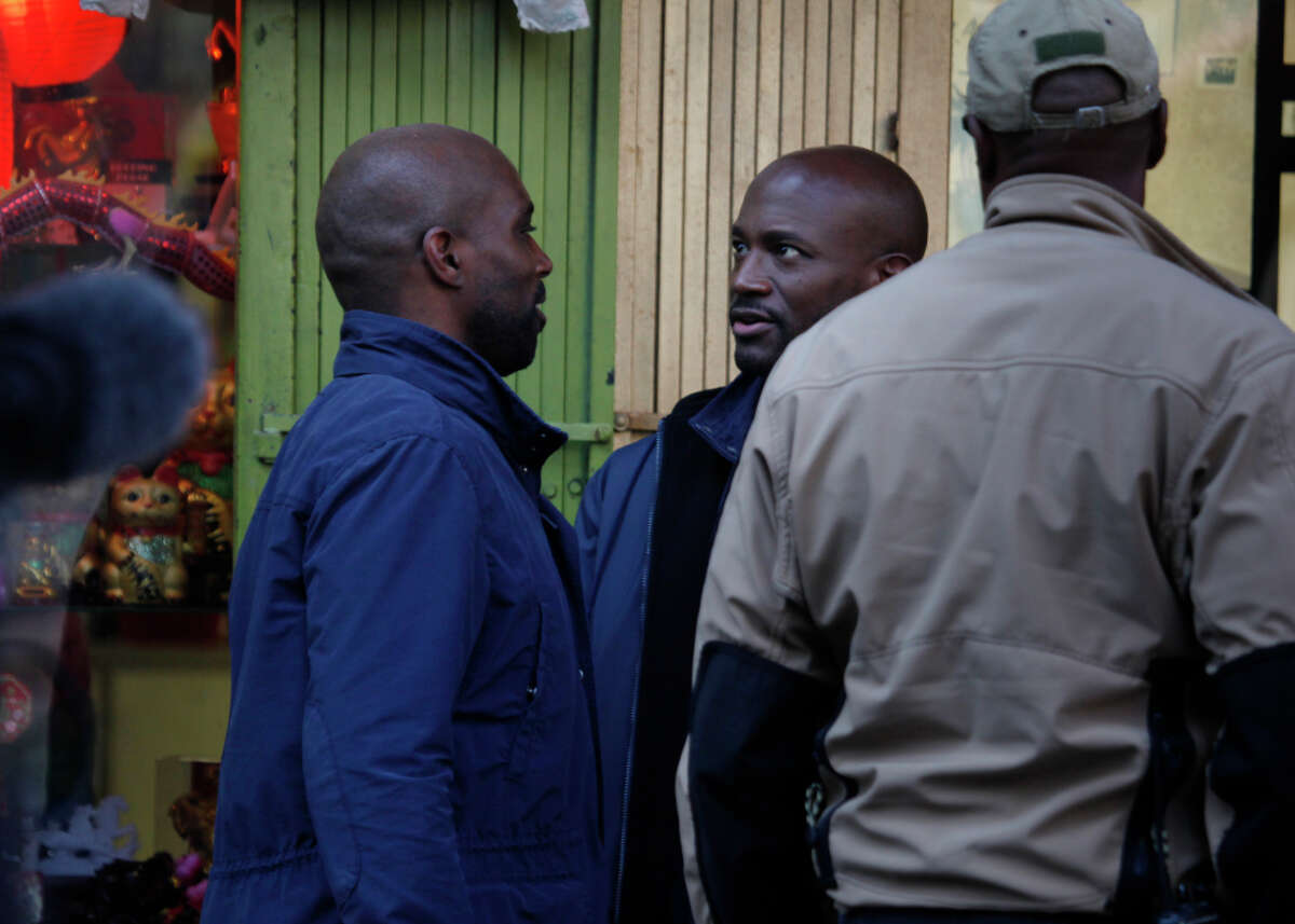 Actor Taye Diggs, right, talks with Horace Knight, left, stunt double for Digg's character Terrance English, between shots on the set of TNT's “Murder in the First” while shooting a scene in San Francisco's Chinatown district.