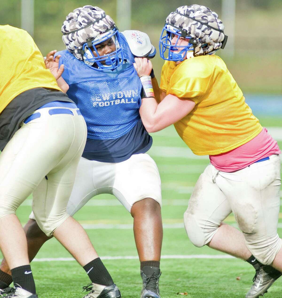 Branden Jackson and Kevin Conte make contact at the line during a Newtown High School football practice. Wednesday, Oct. 15, 2014