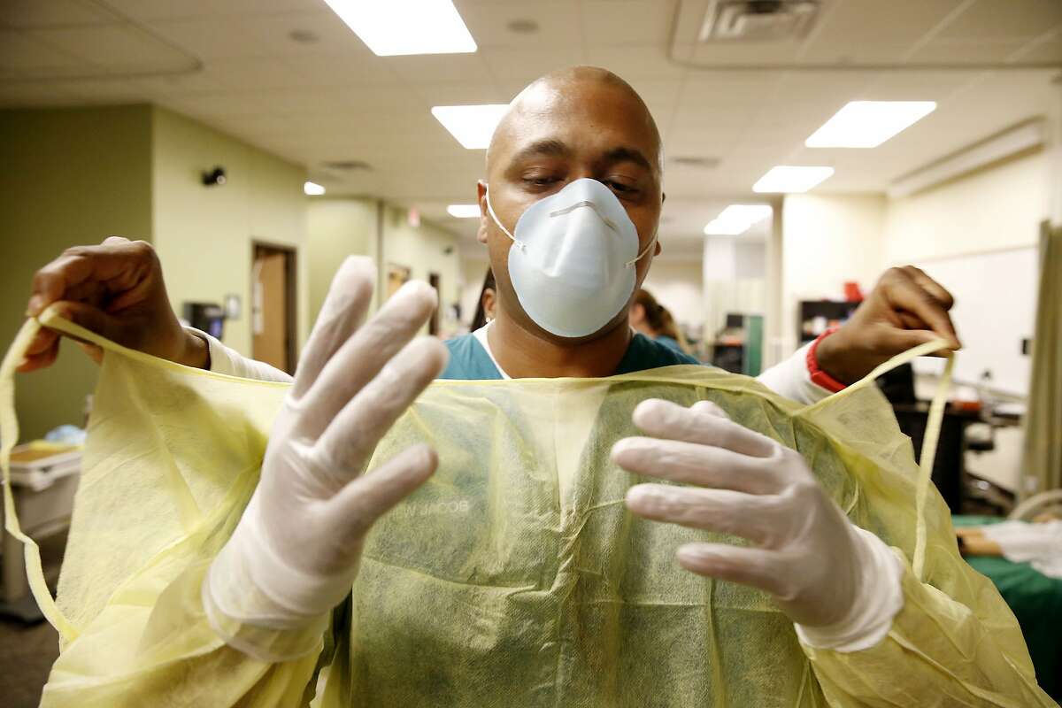 Mathew Jacob, a maternal newborn nursing student, has help removing a gown during a refresher course on personal protective equipment procedure taught at the Brookhaven College School of Nursing in Farmers Branch, Texas, Tuesday Oct. 14, 2014. Nursing, EMS and radiological sciences students will all take the refresh course. A second Dallas hospital worker has tested positive for Ebola, pointing to lapses beyond how one individual may have donned and removed personal protective garb.