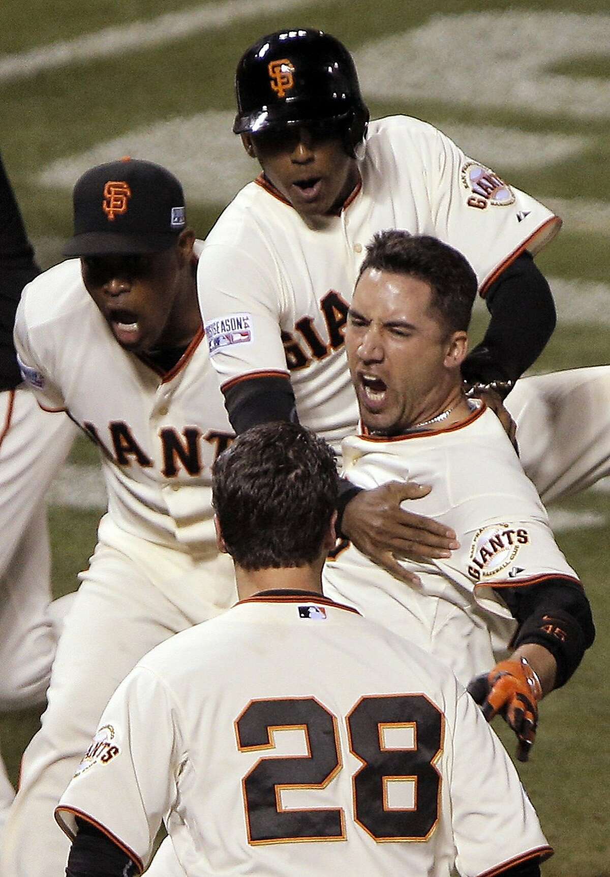The Giants Travis Ishikawa, center, is met at home plate by Santiago Casilla, Joaquin Arias, and Buster Posey as Ishikawa heads toward home plate on his three-run walk off home run during Game 5 of the NLCS at AT&T Park on Thursday, Oct. 16, 2014 in San Francisco, Calif.