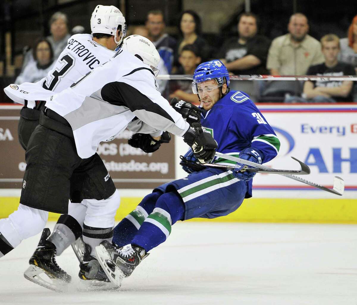 San Antonio Rampage players Alex Petrovic, left, and Greg Zanon, take down Utica Comets' Wacey Hamilton during the first period of an AHL hockey game, Friday, Oct. 17, 2014, in San Antonio. (Darren Abate/AHL)