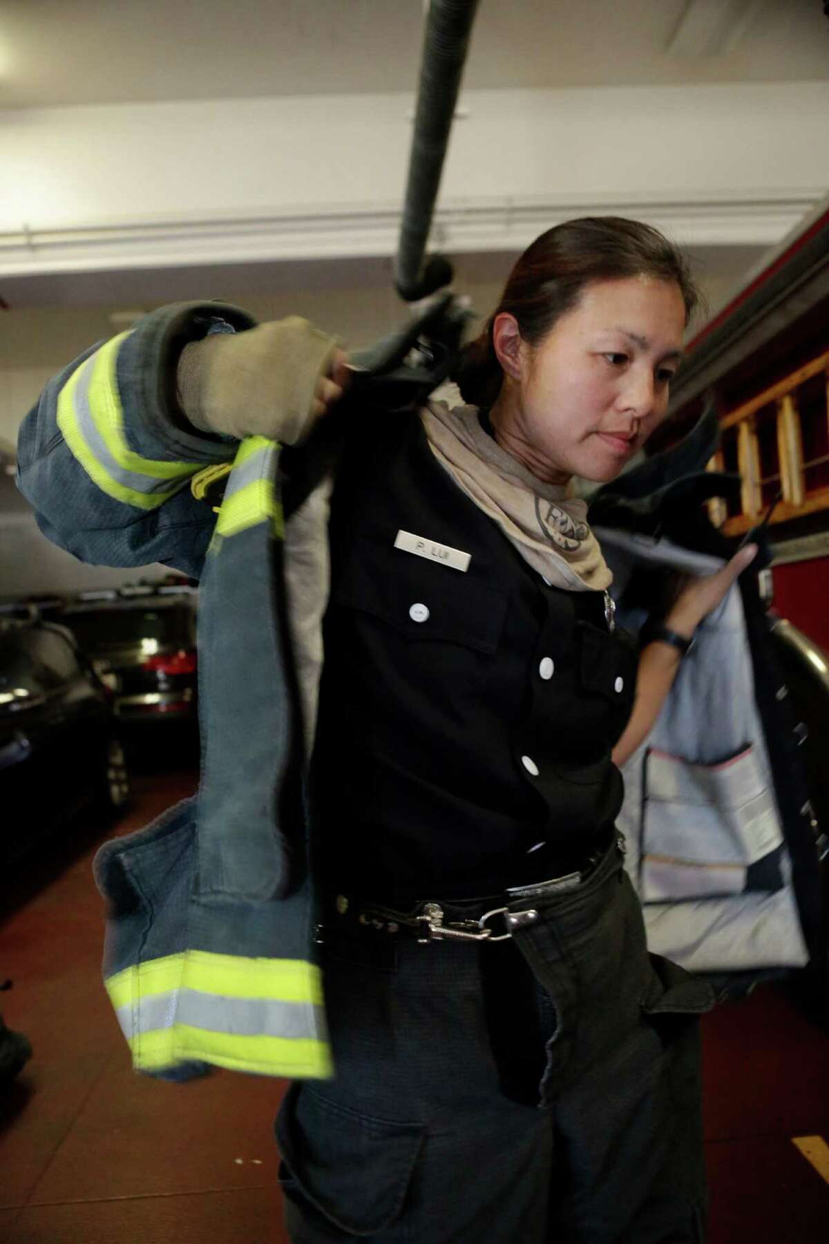 Lieutenant Patty Lui pulls on a jacket in Station 19 in San Francisco on Saturday, October 18, 2014. Lui is participating in a study to determine whether women firefighters are particularly vulnerable to breast cancer. The clothes firefighters wear are a potential source of carcinogens. They become covered in soot and other material when firefighters respond to a fire.