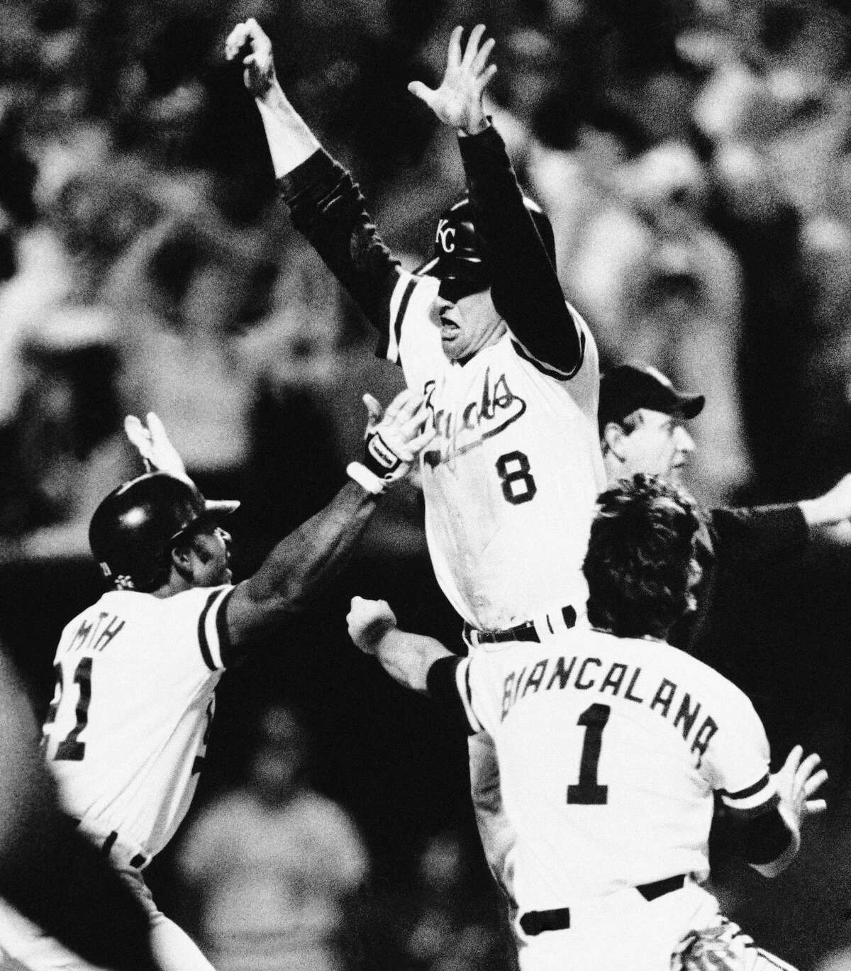 Kansas City Royals Jim Sundberg (8) leaps into the arms of teammates Lonnie Smith, left, and Buddy Biancalana after Sundberg scored in the ninth inning to beat the St. Louis Cardinals, 2-1, in a World Series game, Saturday, Oct. 26, 1985, Kansas City, Mo. (AP Photo/Rusty Kennedy)
