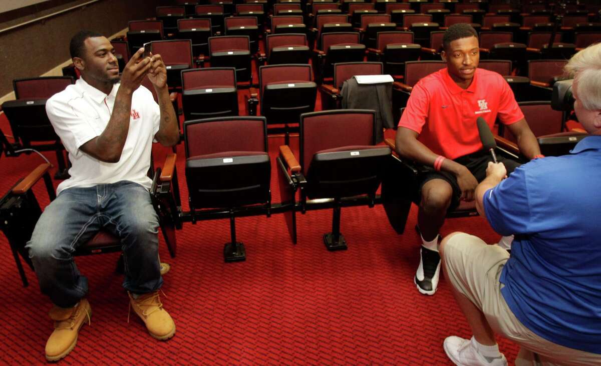 The demands on Mikhail McLean, right, during UH's media day included a conventional interview and posing for a picture ﻿snapped by teammate Jherrod Stiggers, left.