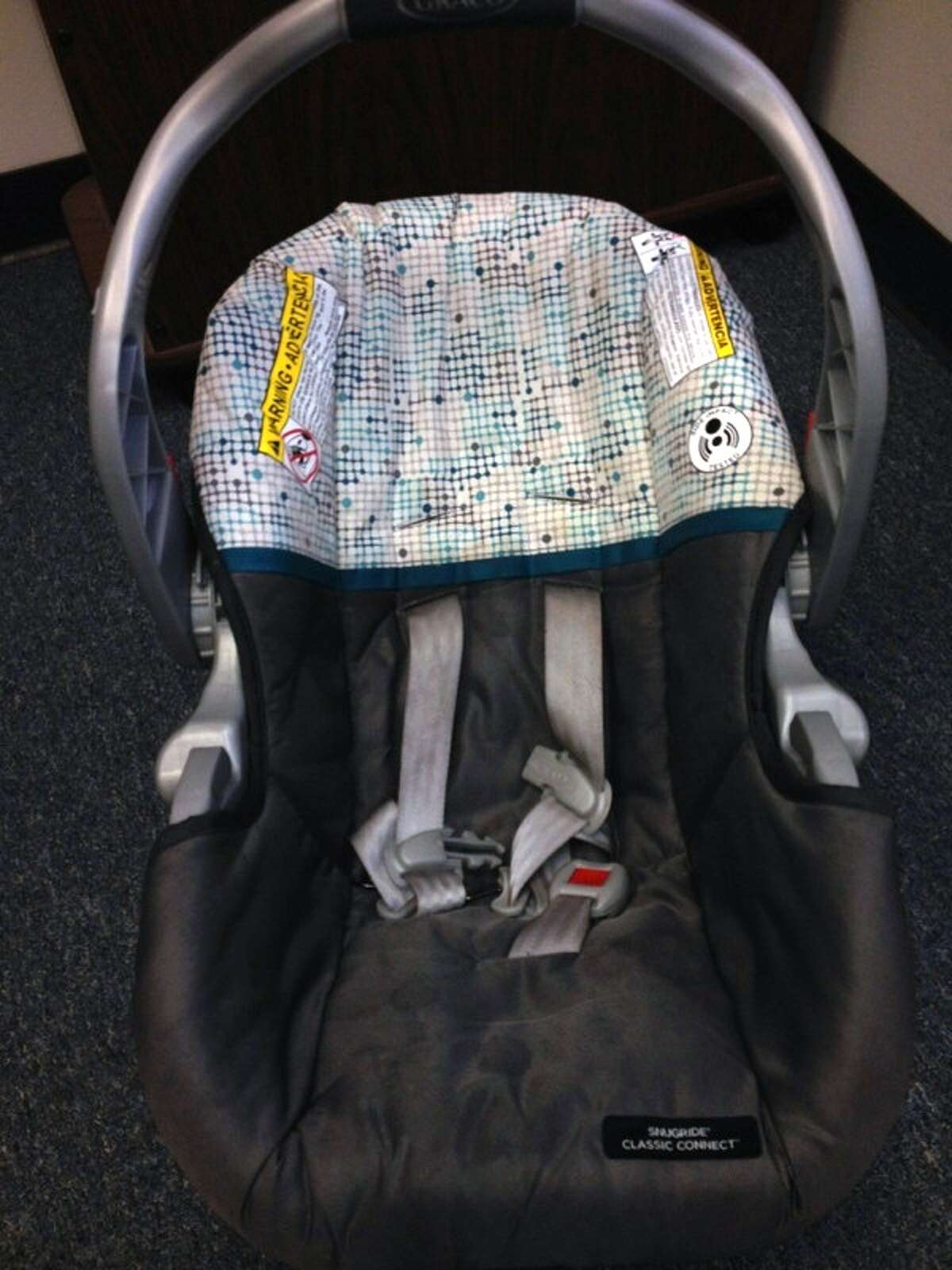 The child's car seat. The baby carrier is a gray Graco SnugRide Classic Connect.