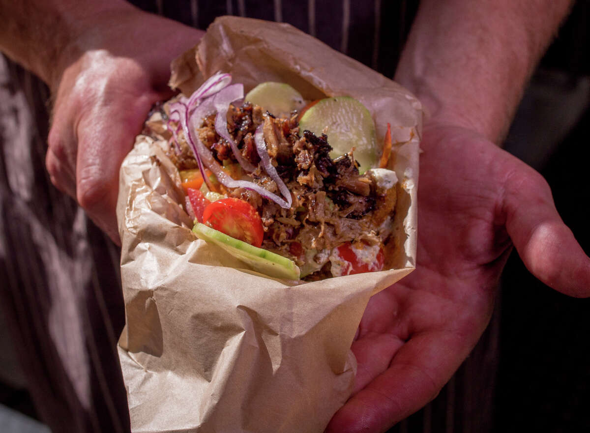 The Whole Beast owner John Fink, far left, can often be found grilling outside his Hall stand at Market and Sixth streets, where tech workers, left, linger. The lamb gyro, above, is made with lamb neck from Don Watson’s farm in Napa.