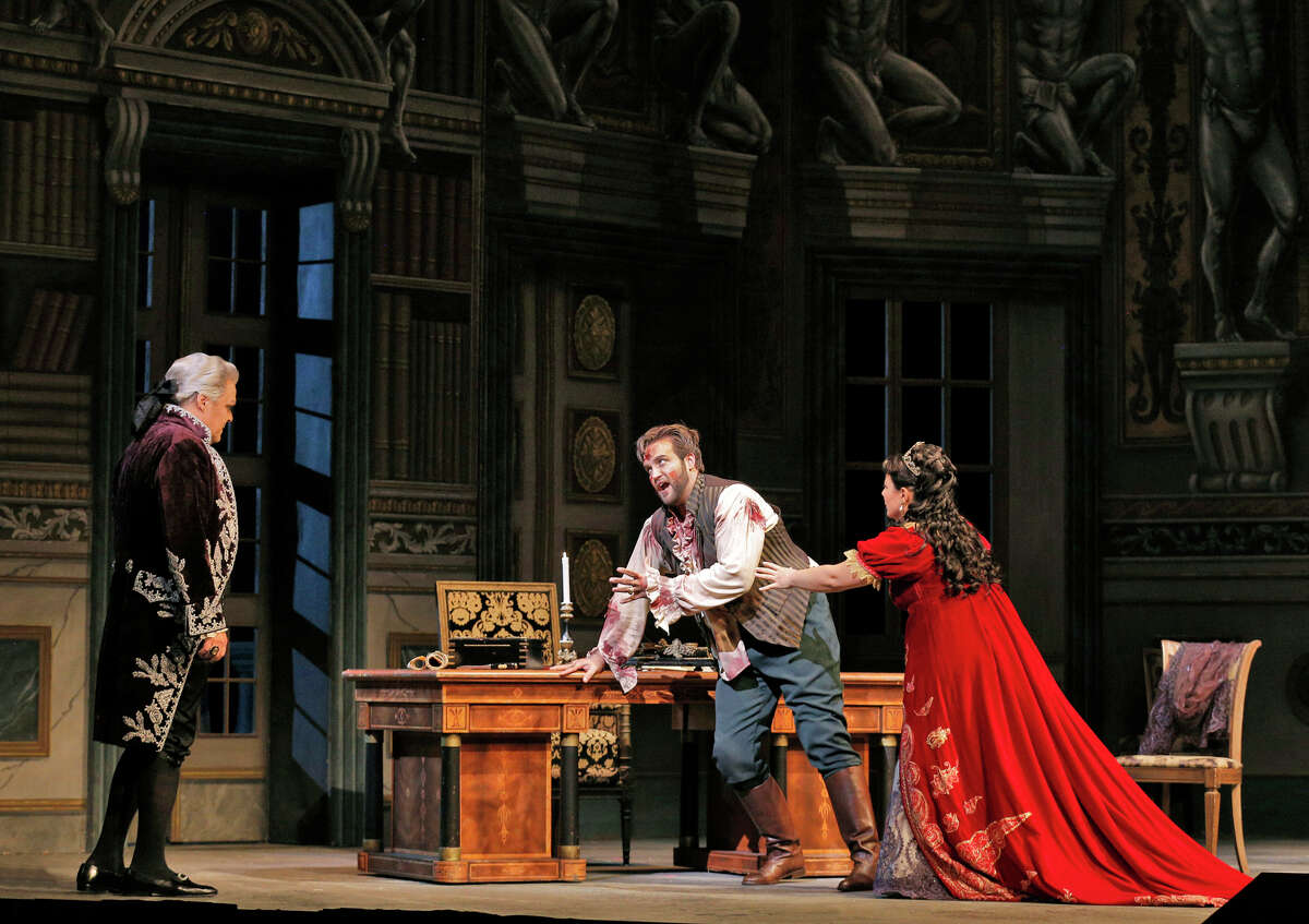 Baritone Mark Delavan (left) as Scarpia, tenor Brian Jagde as Cavaradossi and Lianna Haroutounian as Tosca in “Tosca.”