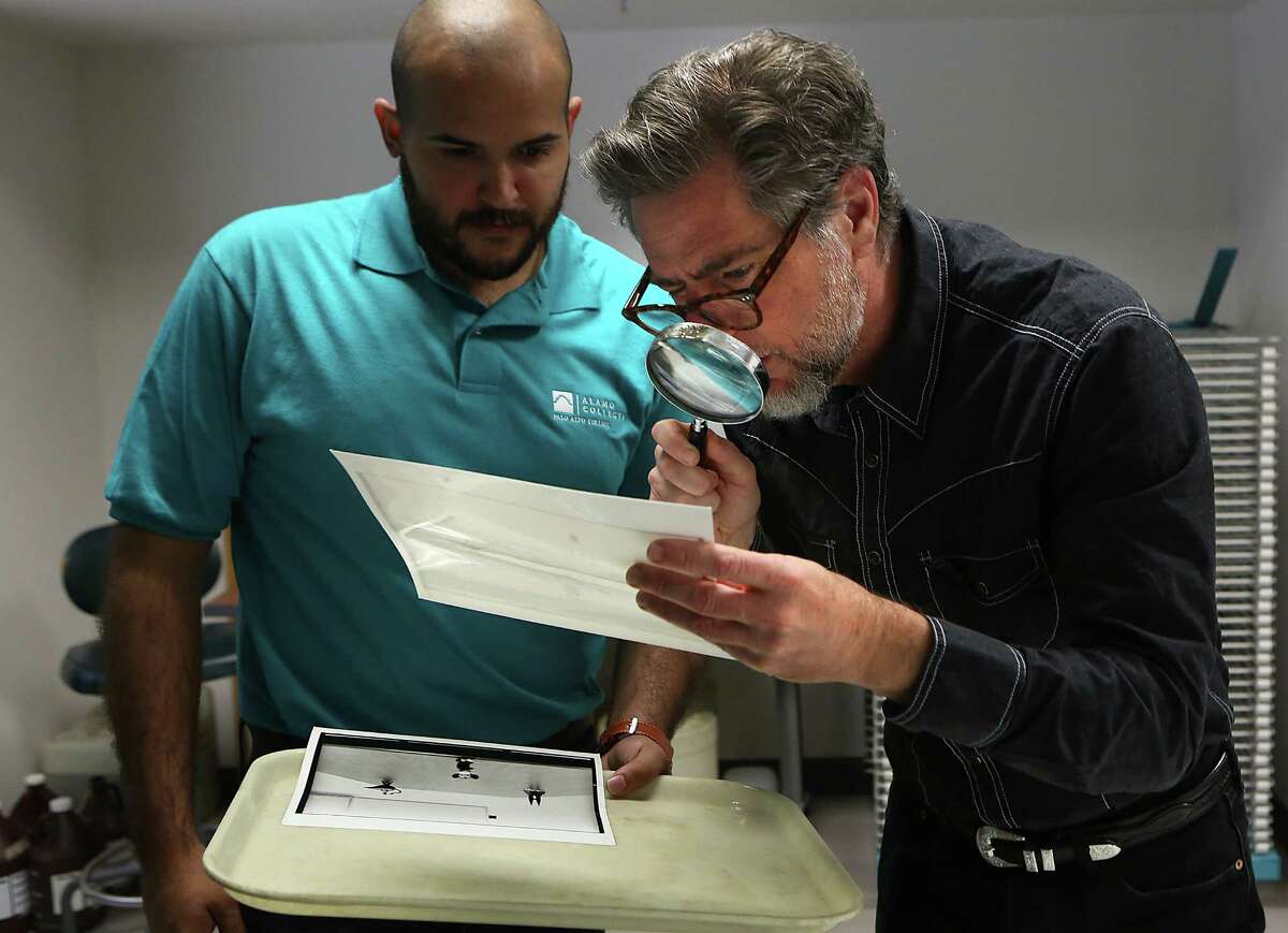 Artist Lloyd Walsh, right, checks the focus and grain on a photo assignment by Michael Maldonado, left. Walsh teaches darkroom photography classes at Palo Alto College. Monday Oct. 20, 2014.