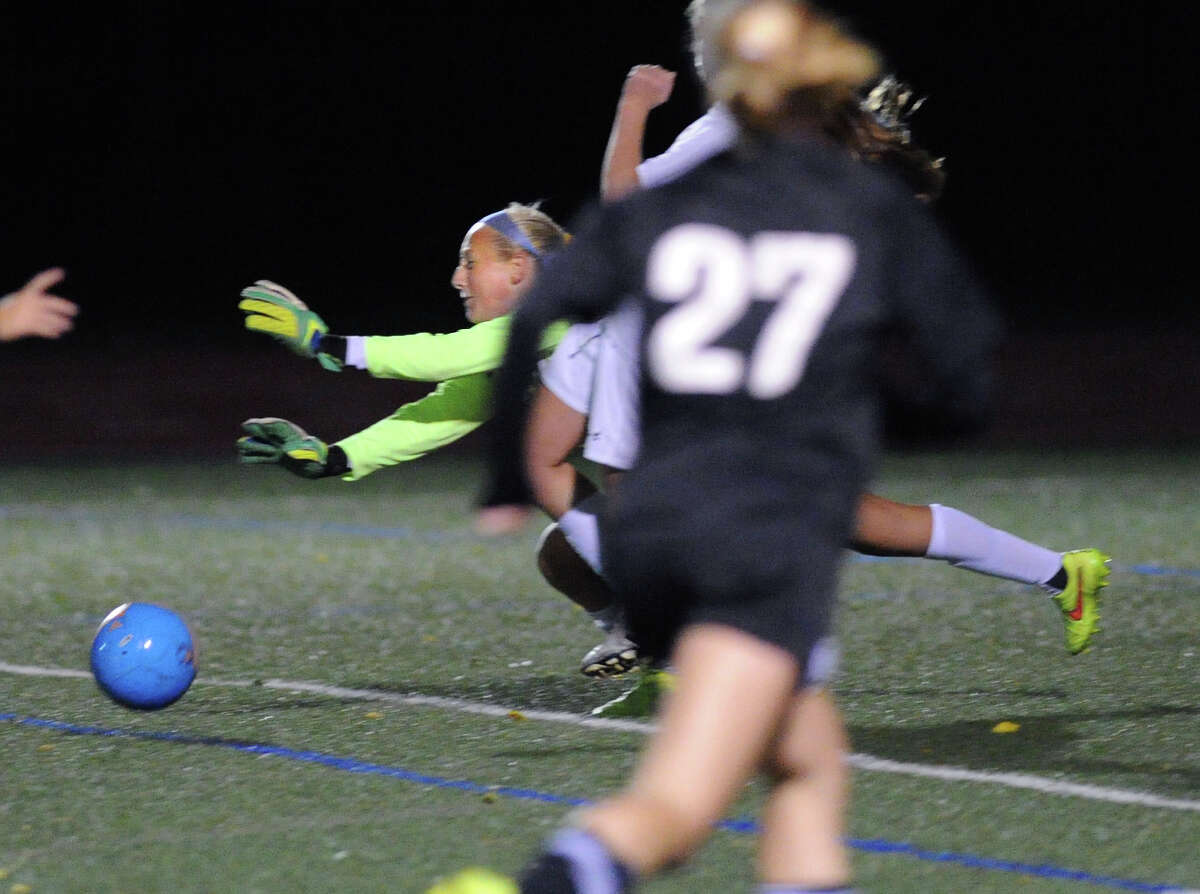 Greenwich goal keeper Emma Barefoot, center, makes a diving stop in the final minutes of the girls high school soccer match between Greenwich High School and Trumbull High School at Greenwich, Conn., Thursday, Oct. 23, 2014. Looking on is Trumbull's Amelia Crosley (#27). Greenwich won the match, 1-0.