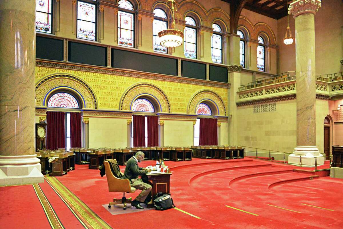 NYS State Assembly's sergeant-at-arms Wayne Jackson sits alone the Assembly Chamber after legislator's desks and chairs have been removed for a pre-season cleaning Friday Oct. 24, 2014, at the State Capitol in Albany, NY. (John Carl D'Annibale / Times Union)