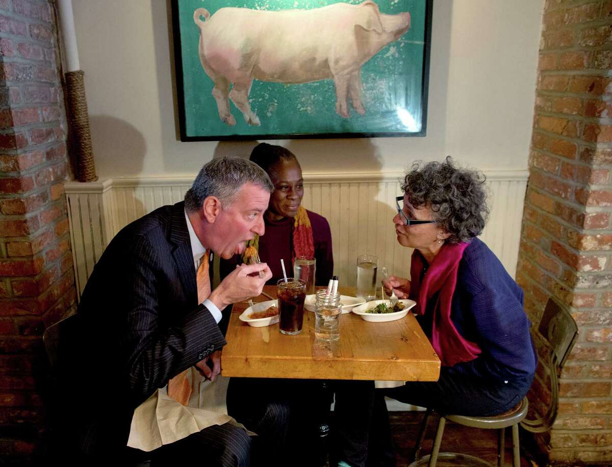 From left, New York City Mayor Bill de Blasio, wife Chirlane McCray, and then-New York City Health Commissioner Dr. Mary Bassett have a meal at The Meatball Shop in New York, Saturday, Oct. 25, 2014, where Dr. Craig Spencer, an Ebola patient, ate just before he became ill. Spencer remained in stable condition while isolated in a hospital, talking by cellphone to his family and assisting disease detectives who are accounting for his every movement since arriving in New York from Guinea via Europe on Oct. 17. (AP Photo/Craig Ruttle) 