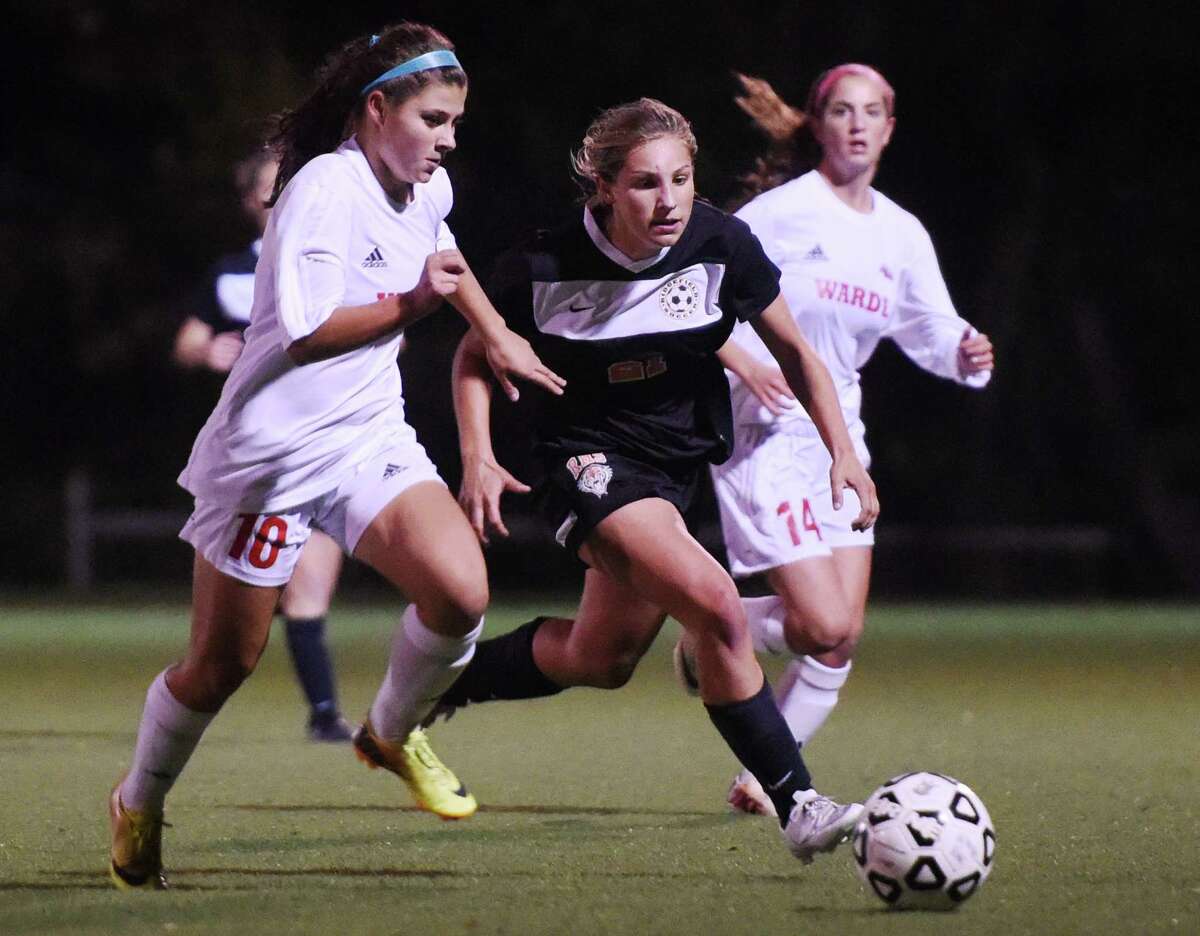 Ridgefield's Katherine Jasminski , center, makes a move past Fairfield Warde's Amelia Andrews (10) and Meredith Nerreau (14) in the FCIAC high school girls soccer semifinal game between No. 6 Ridgefield and No. 2 Fairfield Warde at Wilton High School in Wilton, Conn. Monday, Oct. 27, 2014.