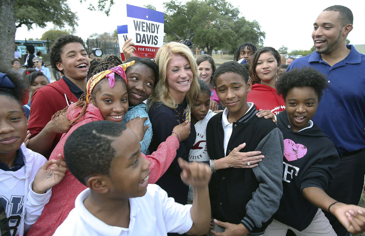 Children crowd around Democratic gubernatorial candidate Sen. Wendy Davis during her campaign stop with Tommy Calvert (right), who is running for Bexar County Commis- sioners Court, at the Claude Black Center on East Commerce Street.