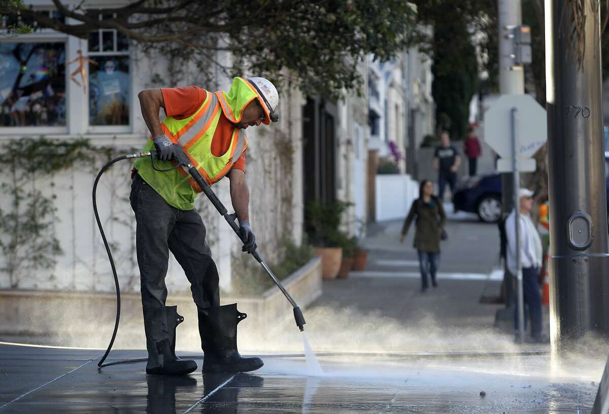 Peter Poliseri washes the sidewalk at 19th Street as construction crews finish the Castro Street improvement project between Market and 19th streets in San Francisco, Calif. on Wednesday, Oct. 29, 2014. Among the improvements are wider sidewalks and crosswalks painted in rainbow colors.