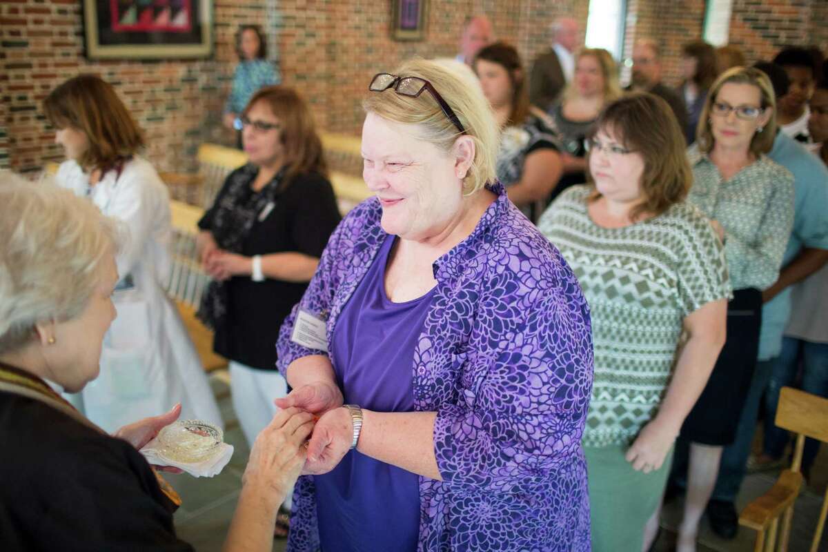 The Rev. Portia Sweet, left, leads a service at the Cockrell chapel of Houston Hospice where where she blesses the hands of nurses, doctors and other hospice staff Wednesday, Oct. 29, 2014 in Houston. This is an annual event to honor those who aid the the dying. The process essentially is prayer and and rubbing lavender oil on the aforementioned hands.