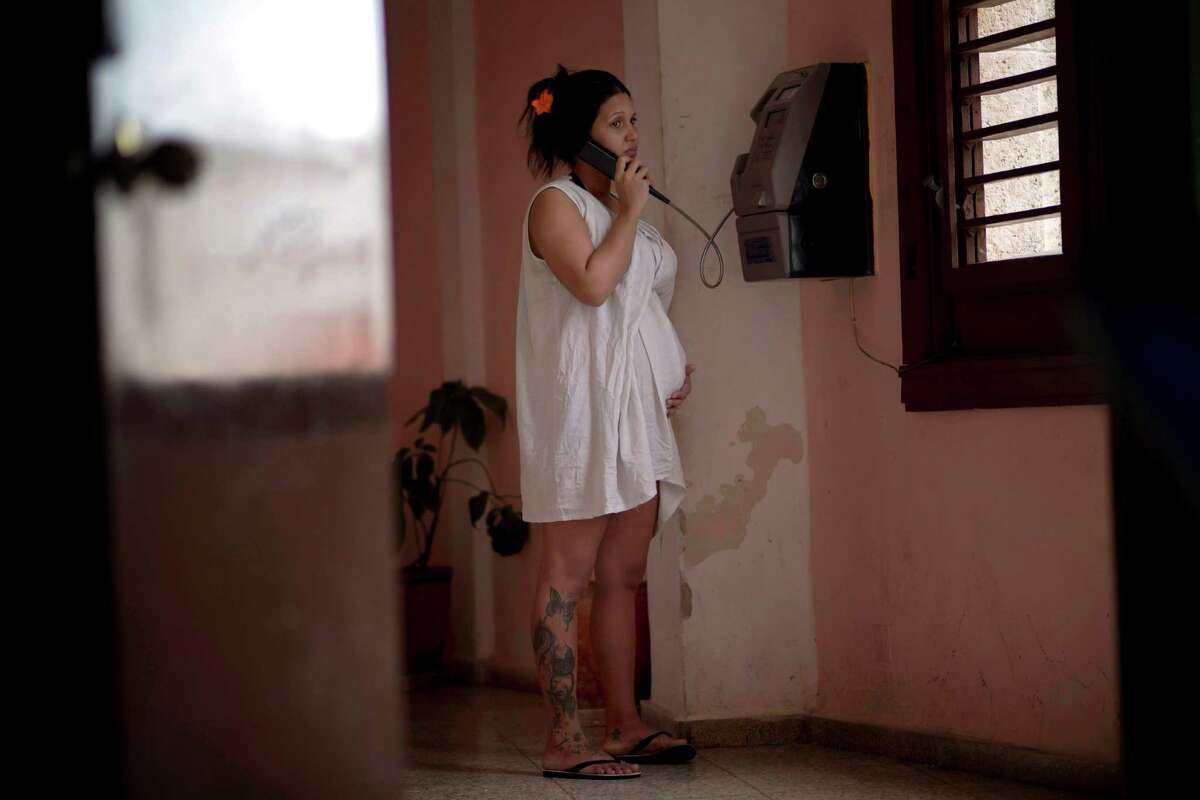In this Oct. 22, 2014 photo, a pregnant woman holds her belly while she talks on a public phone at a special maternity unit for high-risk pregnancies in Havana, Cuba. The country's low birth rate problem is a result of some of the most notable successes of its 55-year-old socialist revolution: more working women with professional jobs and universal access to medical care, which includes contraception and free, legal abortion. Itâs also a product of its failures: a lackluster economy, persistently high levels of emigration by young people and an island-wide housing shortage. (AP Photo/Ramon Espinosa)