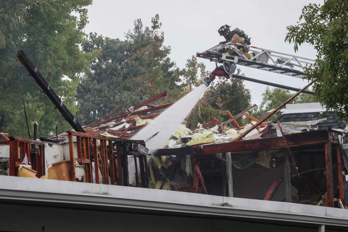 A firefighter sprays water on the wreckage of an apartment building in Walnut Creek that was hit by an explosion. Two people were injured in the blast.