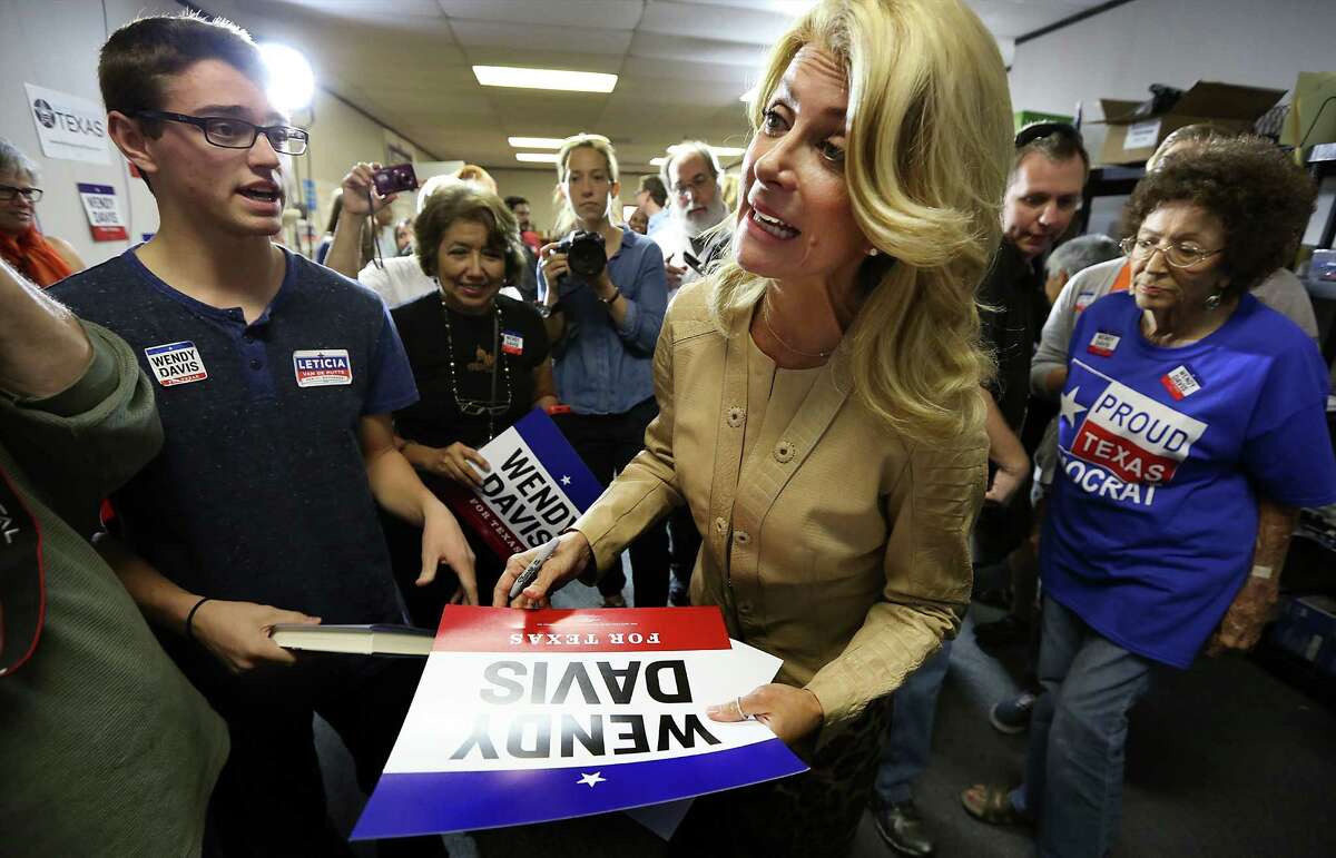 Senator Wendy Davis signs posters as she makes a stop in San Antonio at her Northeast Side field office, which is probably her last stop in San Antonio before election. At left is Gabrien Gregory who voted for the first time this year and Wandy Lay, right. Friday, Oct. 31, 2014.