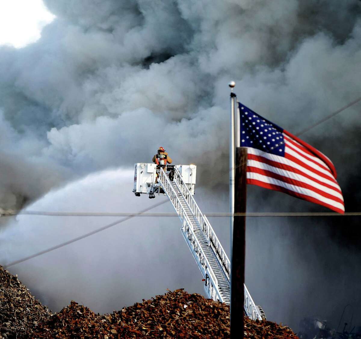 Houston Firefighters work to contain a large fire at the intersection of Harrisburg and Navigation near the Houston Ship Channel, Saturday, Nov. 1, 2014, in Houston. It appeared to be scrapped cars on fire.